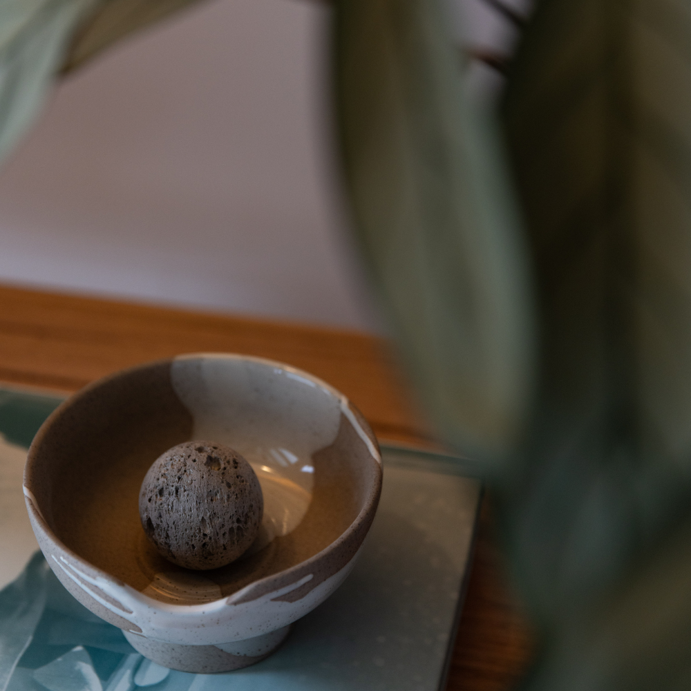Small ceramic bowl with a textured ball inside on a wooden surface