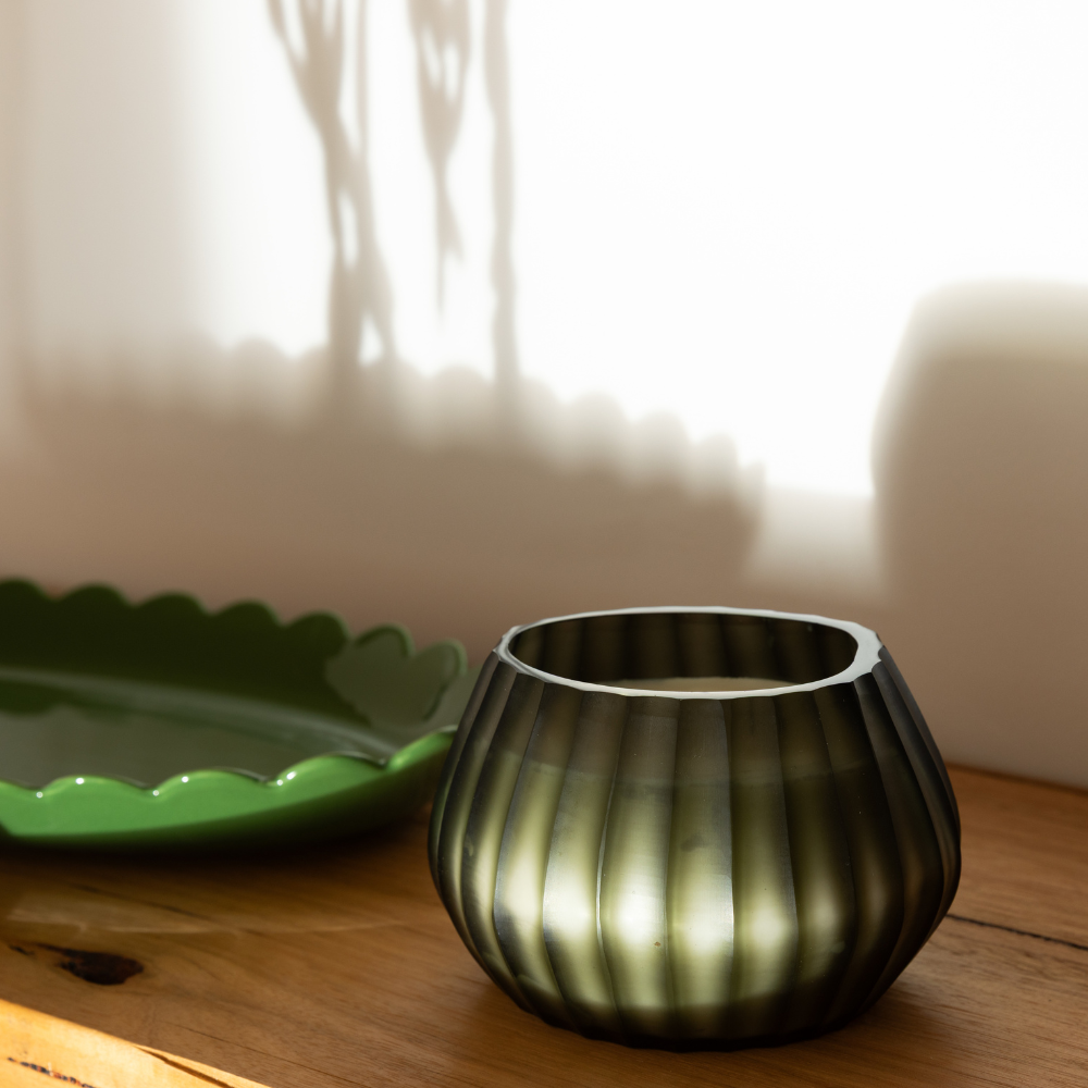 Aura Moss Candle burning, releasing Wanderlust fragrance in hand-carved glass vessel