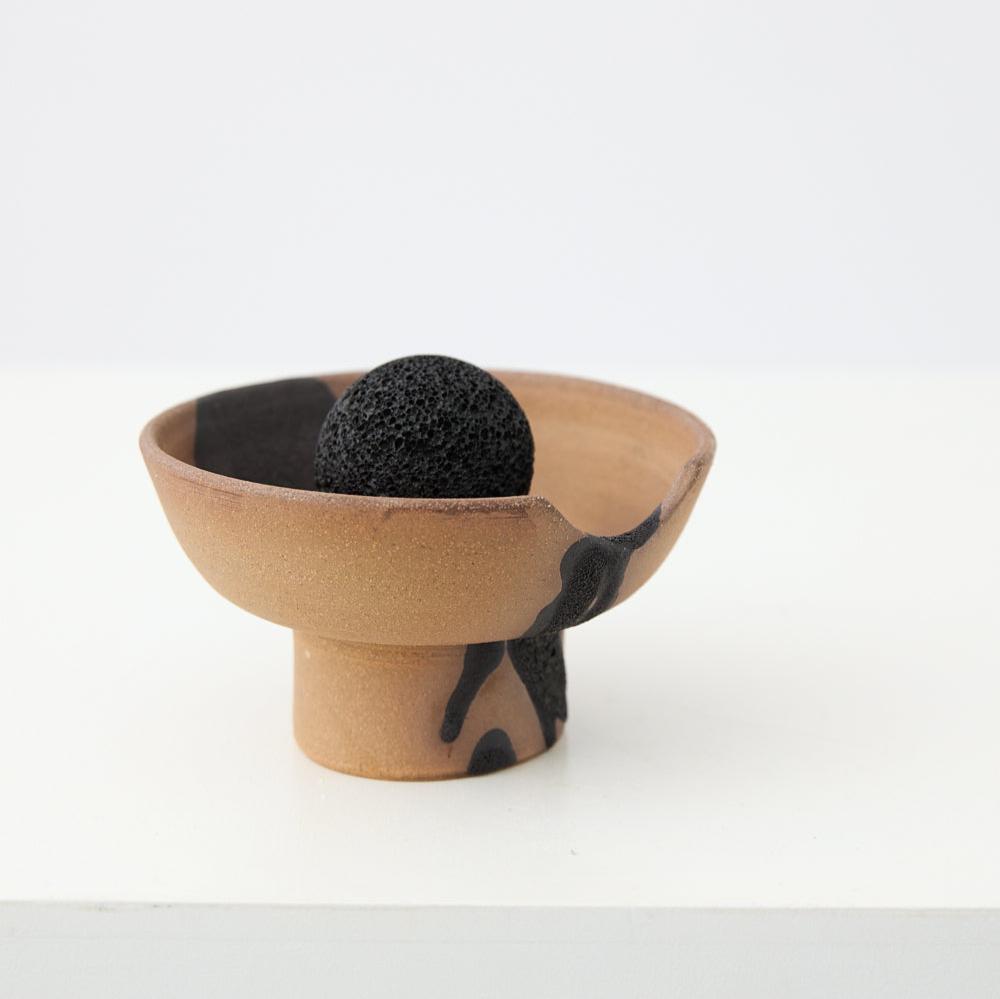 Close-up of volcanic rock resting on handcrafted ceramic diffuser tray with volcanic glaze finish
