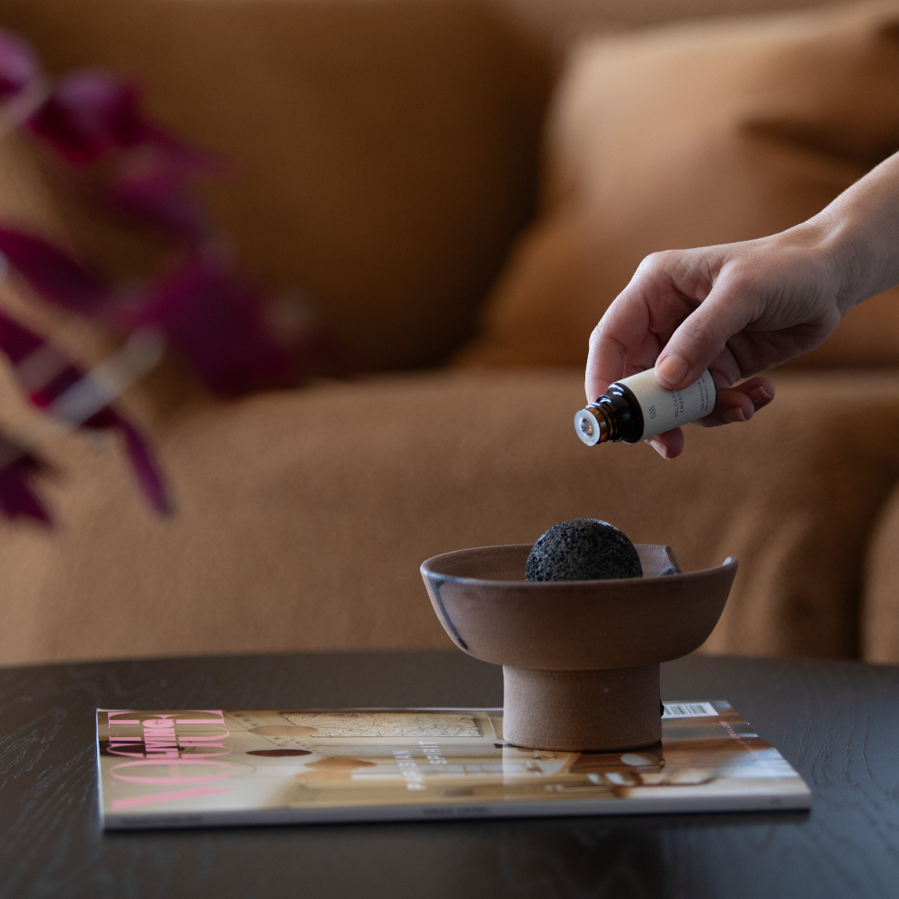 Close-up of volcanic rock resting on handcrafted ceramic diffuser tray with deep volcanic glaze finish