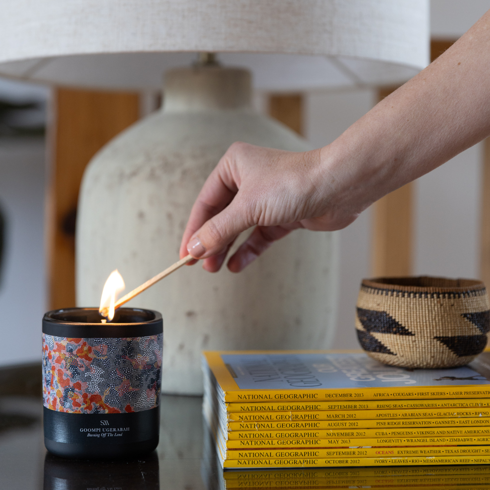 Burning Off The Land Artist Series Candle styled in a warm natural setting with earthy tones