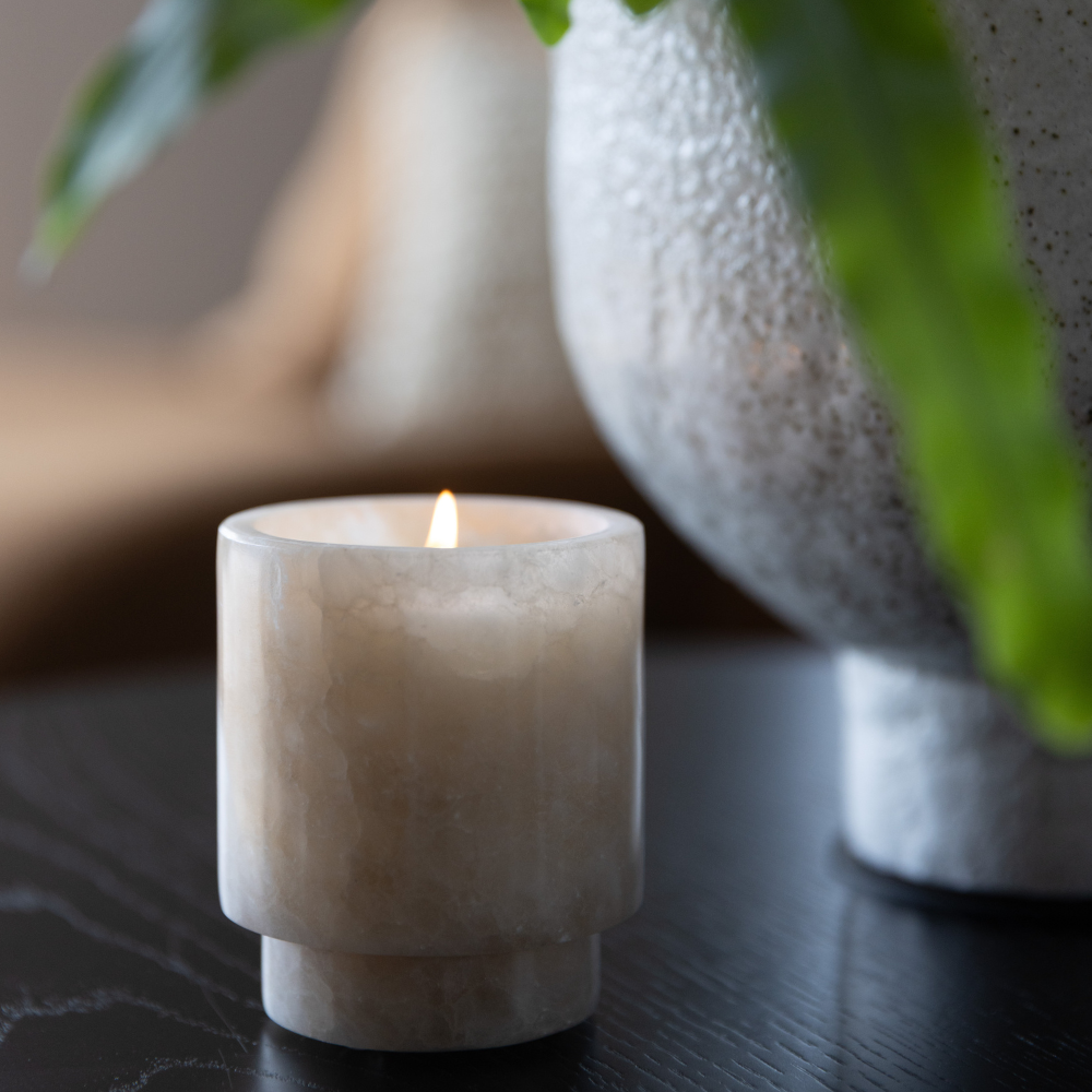 Ambiente Alabaster Candle burning, releasing Peppered Orchid fragrance through translucent stone vessel