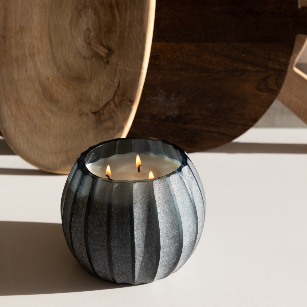 Mouth-blown Atolla Blue Bottle Candle styled on a marble surface, reflecting light through rich blue glass