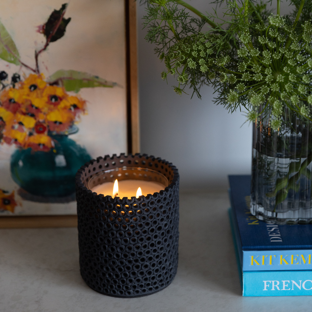 Coralite Ebony Candle burning, releasing Noir fragrance in handmade ceramic vessel